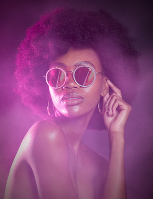 A beautiful black lady looking into the distance wearing sunglasses